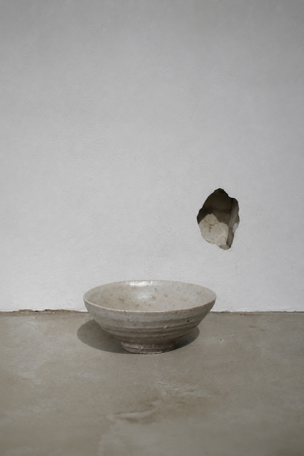 Plaster wall with chipped hole, quiet negative space